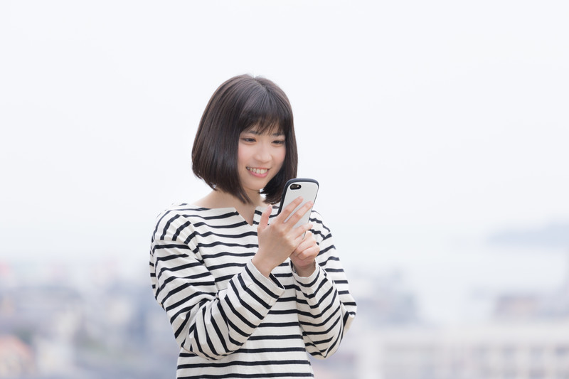 スマホを笑顔で見る女性